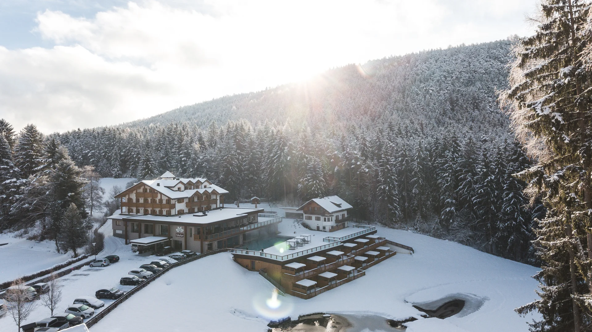 Entschleunigen und genießen in diesem Hotel nahe Bruneck Hotel in verschneiter Berglandschaft mit Wald und Sonnenlicht