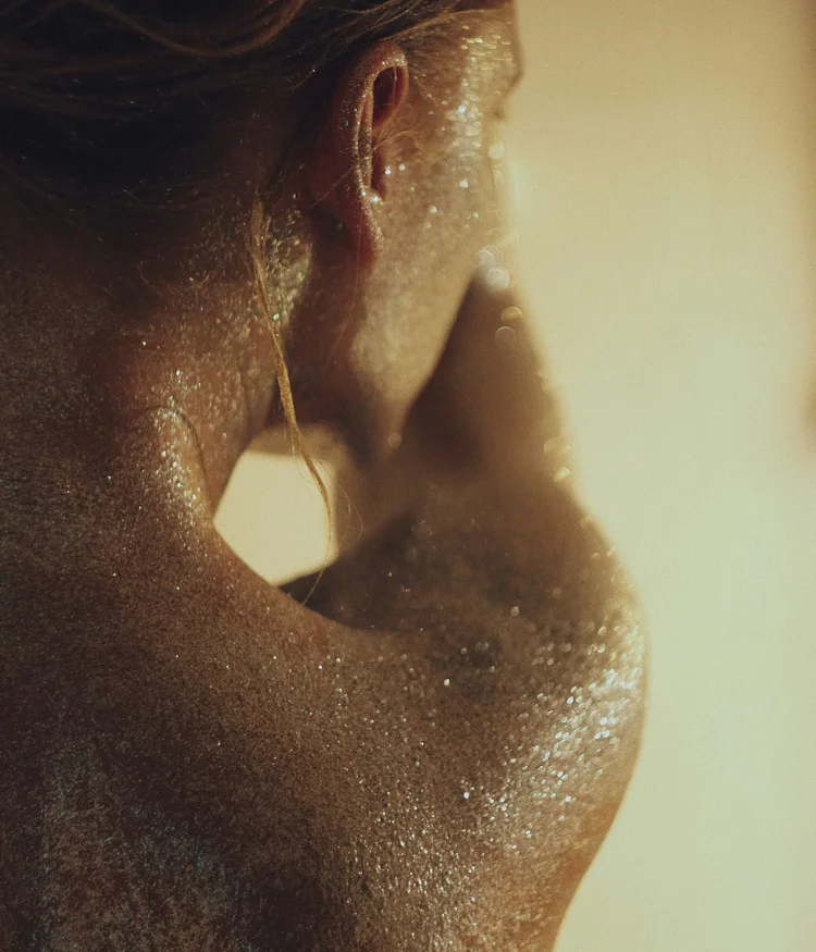 Close-up of a person with glittery skin and wet hair