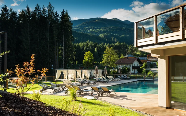 Pool mit Liegestühlen und Bergblick an einem sonnigen Tag