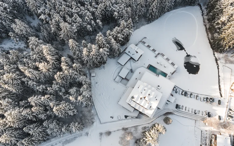 Absolutely stunning impressions Aerial view of a snow-covered building next to forest and parking lot