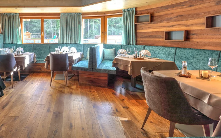 Gemütlicher Restaurantbereich mit Holzboden und türkisfarbenen Sitzbänken