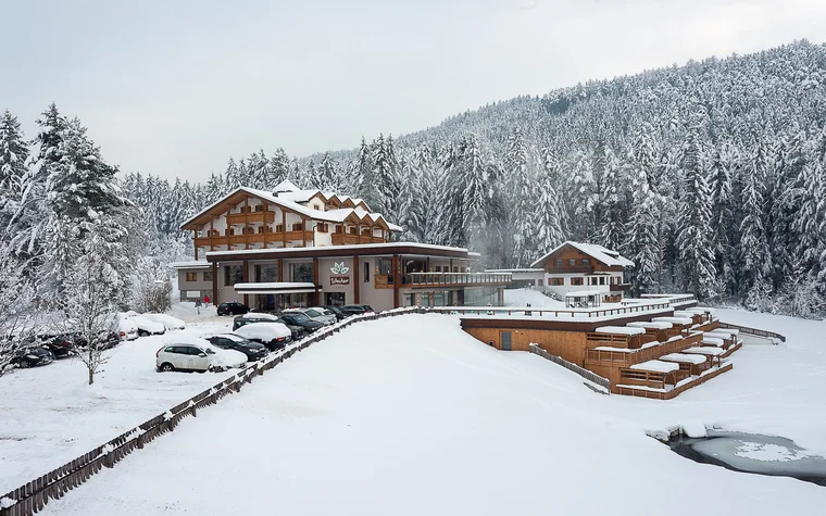 Absolutely stunning impressions Hotel building in snowy forest with frozen pond and parked cars