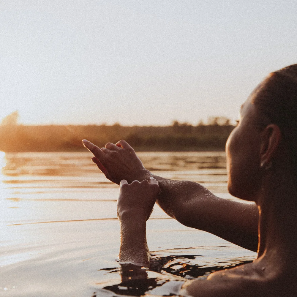 Green Lake Hotel Weiher: 4-star superior hotel in Val Pusteria Woman in water at sunset looking at her arm