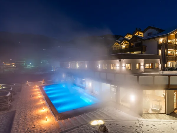 Hotel con spa a Brunico: la poesia della quiete Piscina esterna illuminata con vapore vicino a hotel innevato di notte