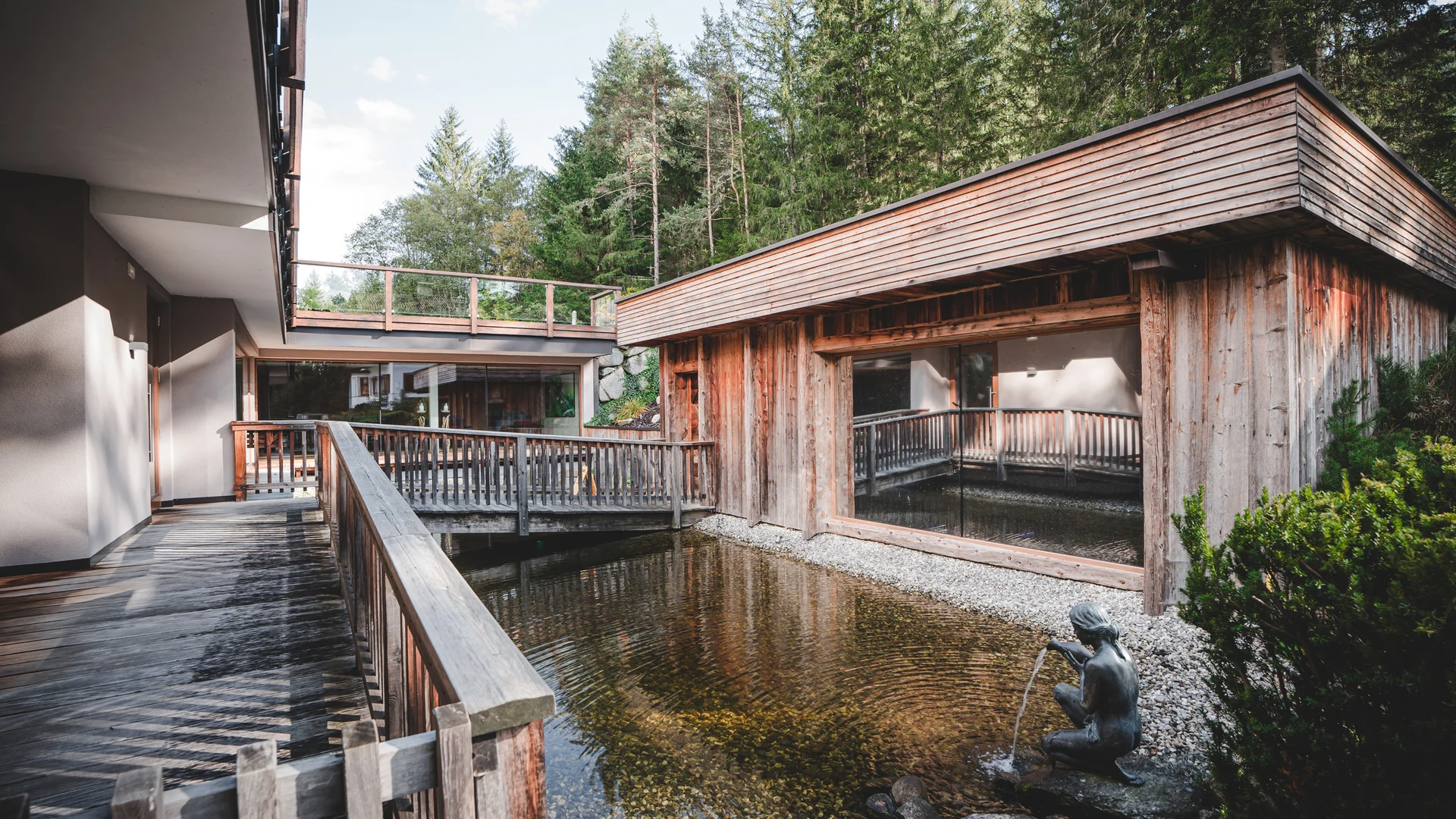 Green Lake Hotel Weiher: 4-star superior hotel in Val Pusteria Wooden terraces and pond with fountain statue in a forest resort