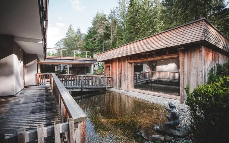 Holzterrassen und Teich mit Brunnenfigur in einem Waldresort