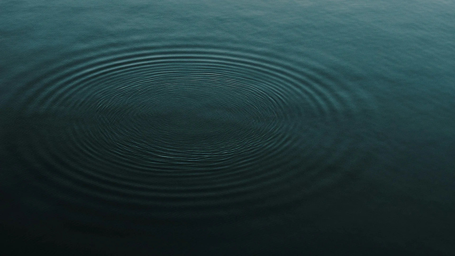 Sanfte Wellenringe auf ruhiger Wasseroberfläche bei Dämmerung