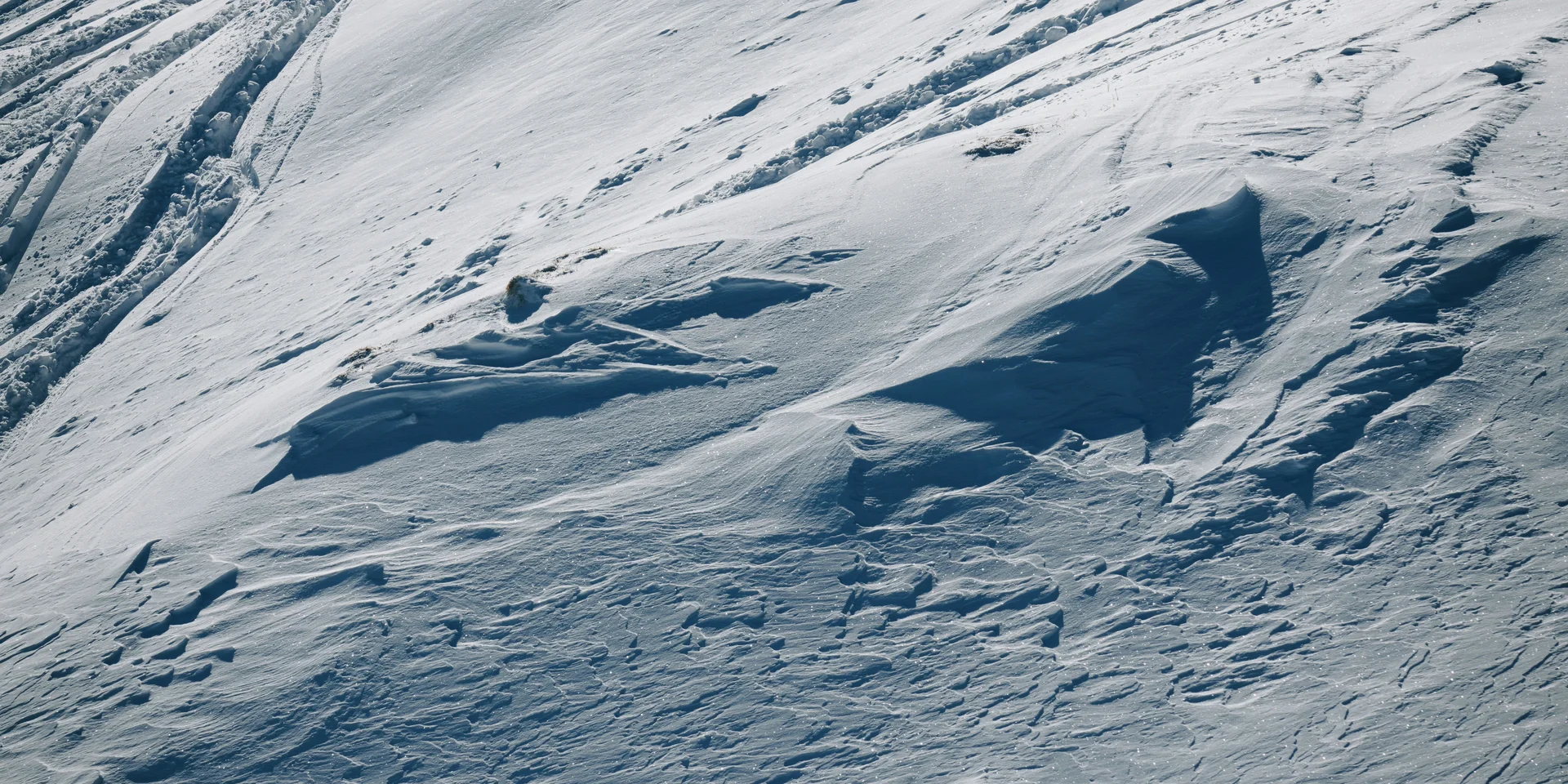 Schneebedeckte Hänge mit Skispuren im Sonnenlicht