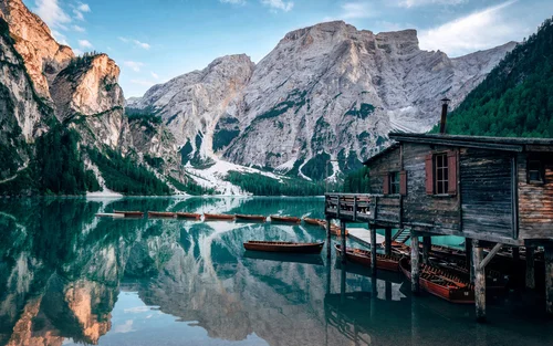 Capanno di barche in legno su lago di montagna con montagne riflesse