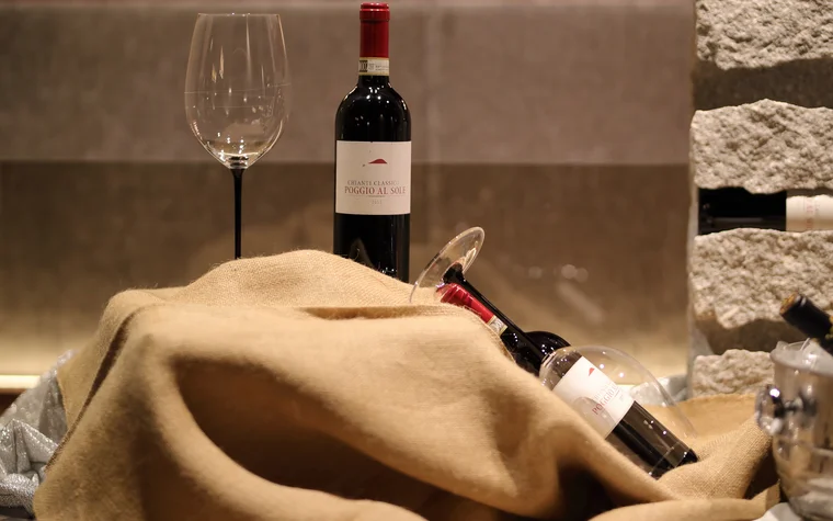 Flasche Chianti Classico mit zwei Weingläsern auf beigem Stoff