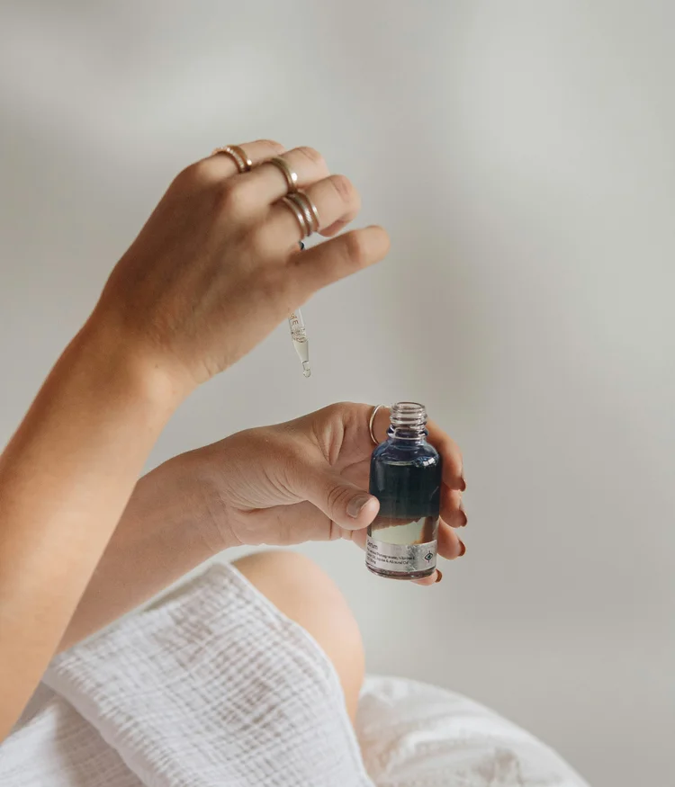 Hand holding dropper and bottle with blue liquid