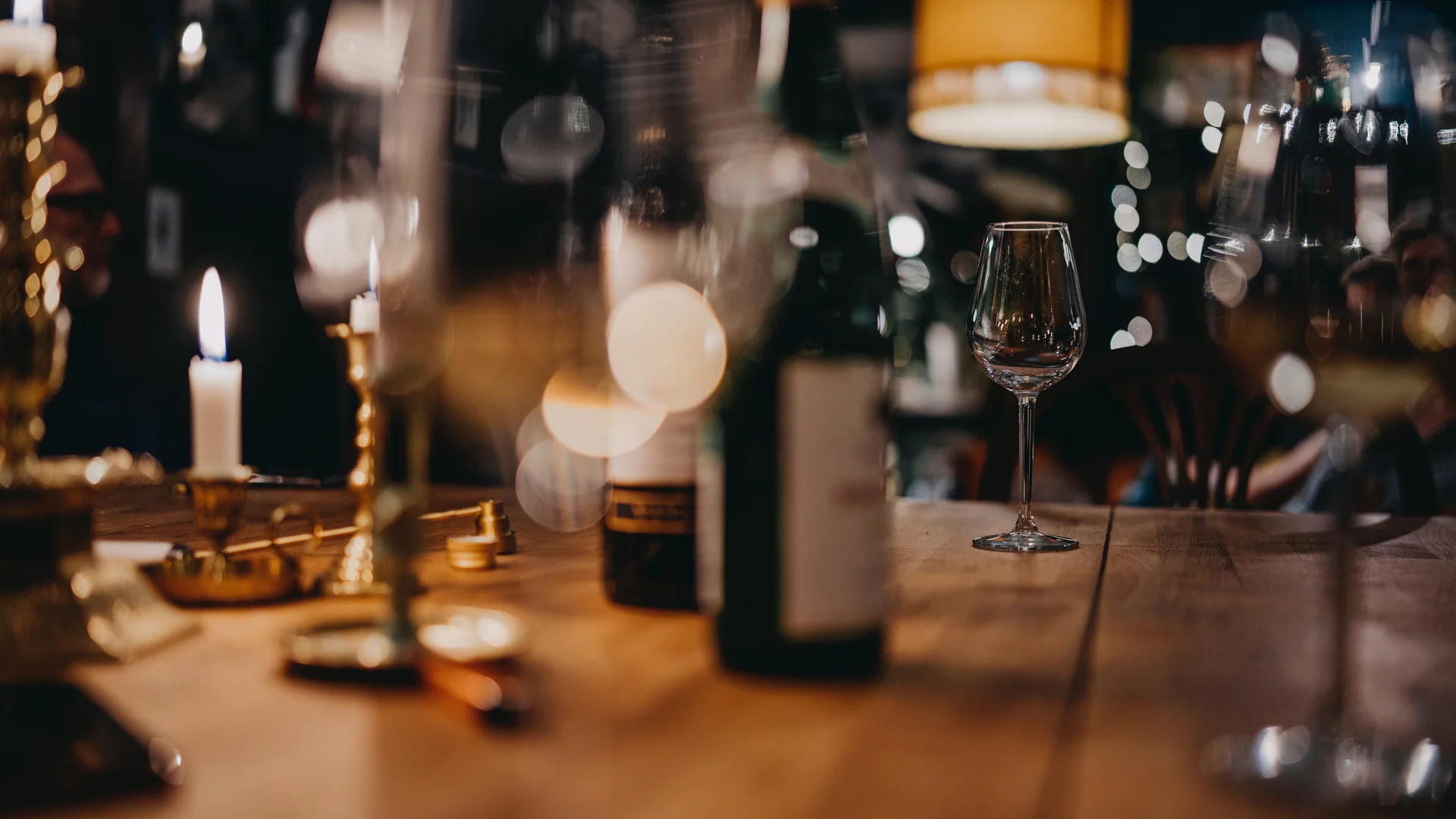 Essen in Ihrem Genusshotel in Südtirol Weinglas und Kerzen auf einem Holztisch in gemütlicher Bar