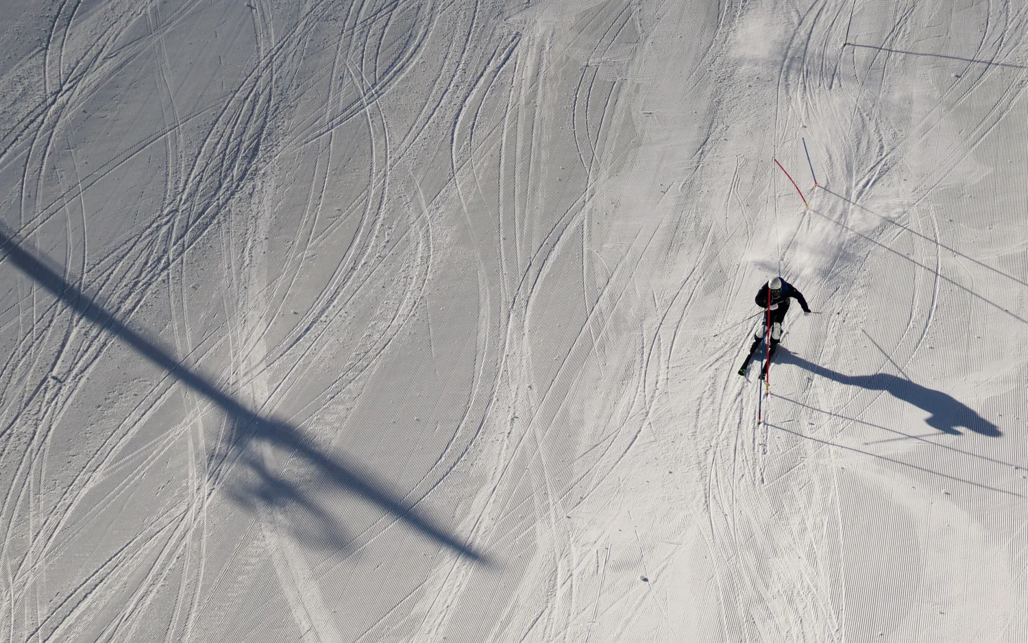 Skifahrer auf verschneiter Piste mit Spuren und Schatten von Sessellift