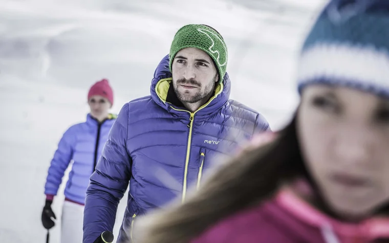 Da cartolina, queste immagini Uomo con berretto verde e giacca invernale viola, con altre persone sulla neve