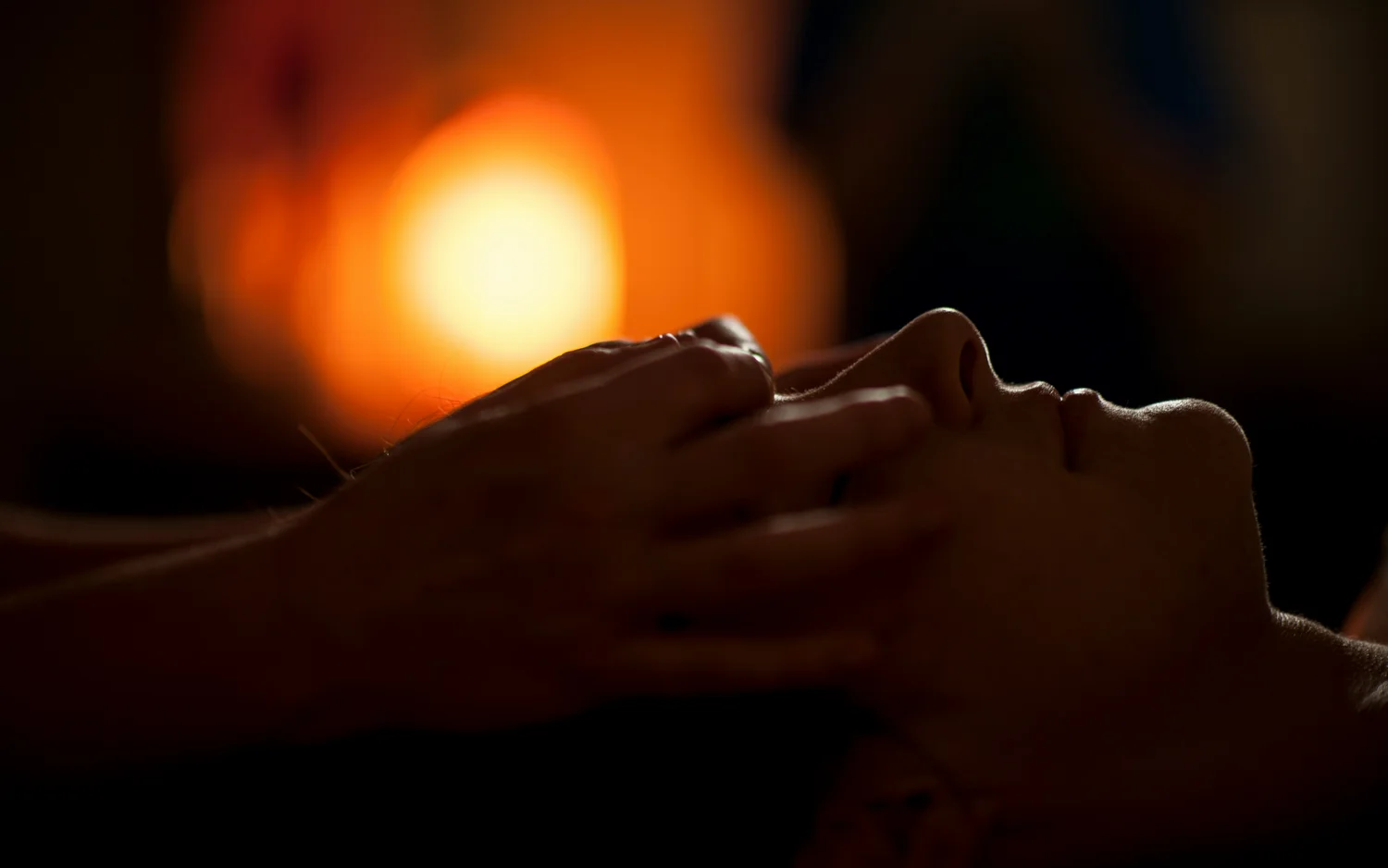 Person receiving a relaxing facial massage with warm light in background