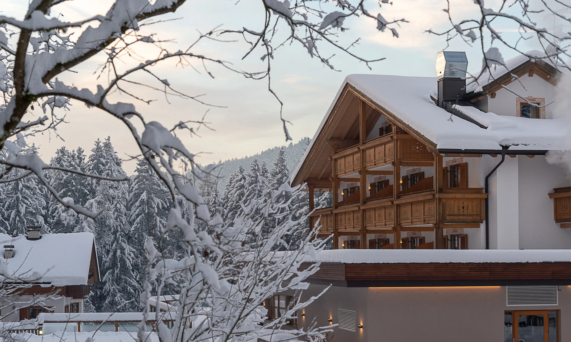 Il segreto di rallentare in questo hotel vicino a Brunico Hotel innevato con balconi in legno in un paesaggio invernale boschivo