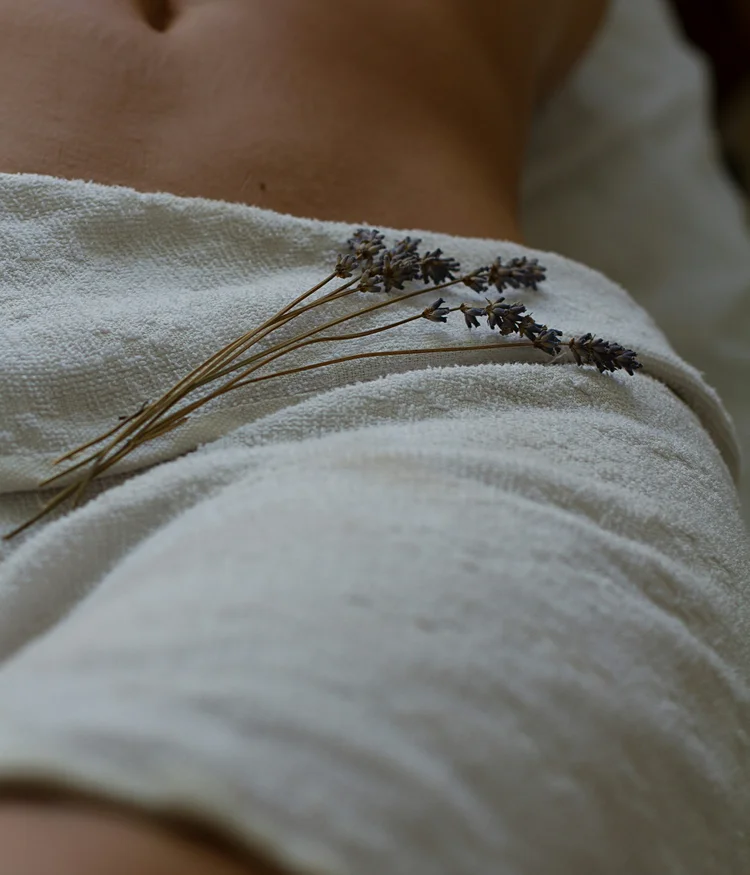 Close-up of a stomach with a white towel and lavender sprigs on top