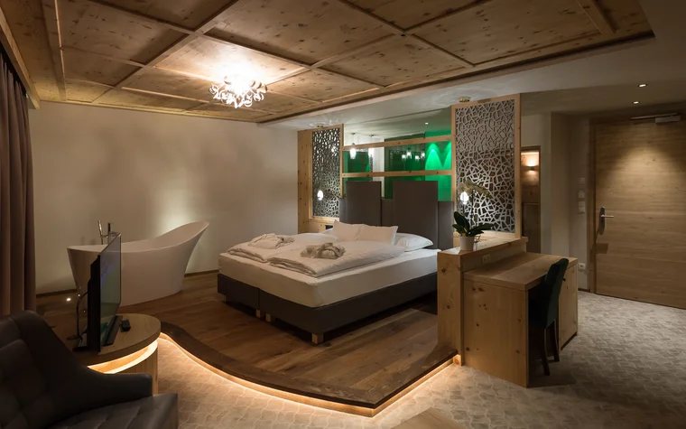 Modernes Hotelzimmer mit Doppelbett, Badewanne und Holzmöbeln