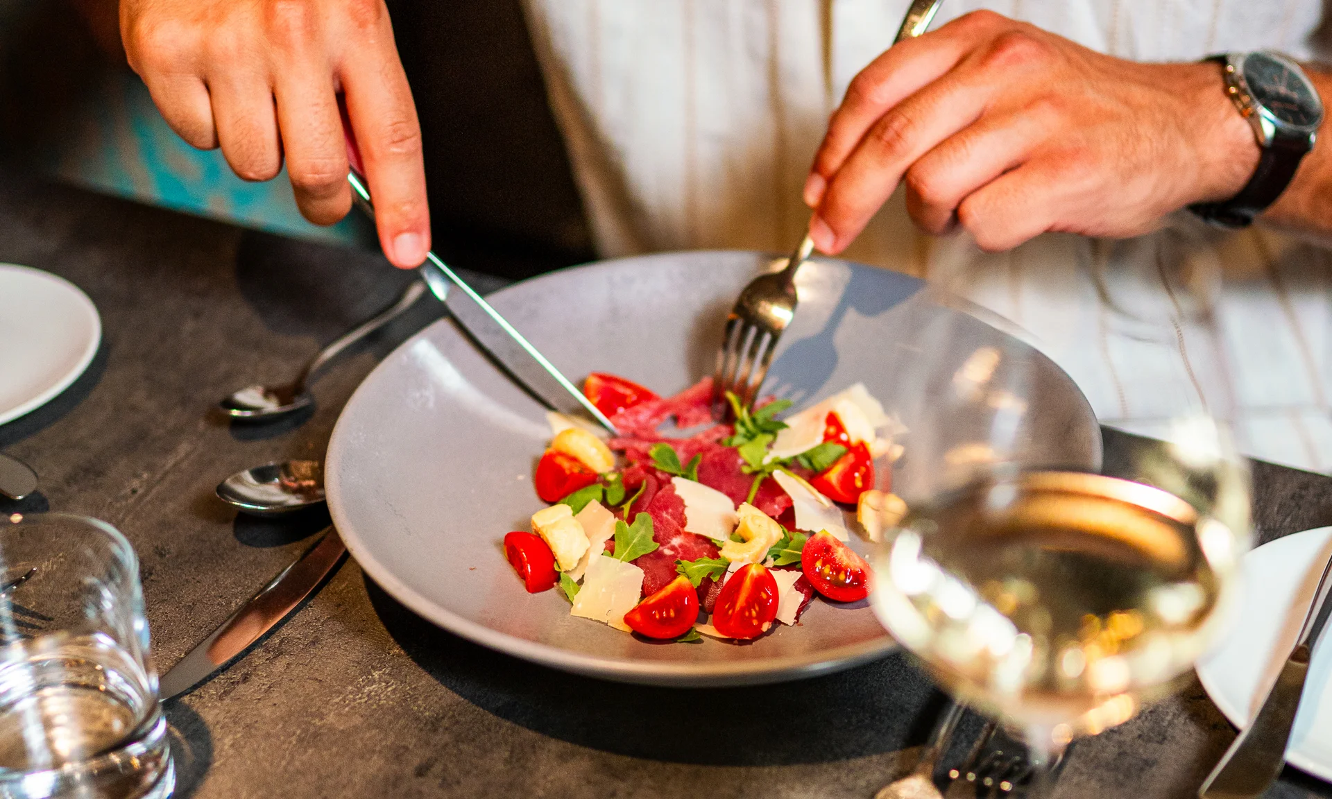 Il segreto di rallentare in questo hotel vicino a Brunico Persona che taglia insalata con pomodori e formaggio su tavolo grigio