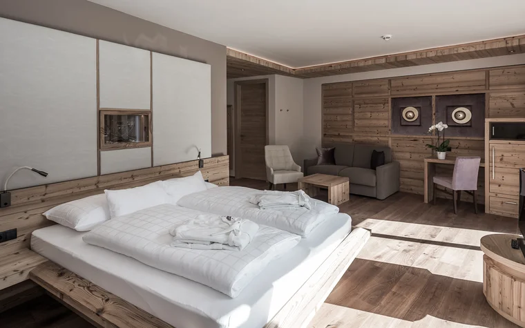Helles Hotelzimmer mit Doppelbett, Sofa und Holzmöbeln
