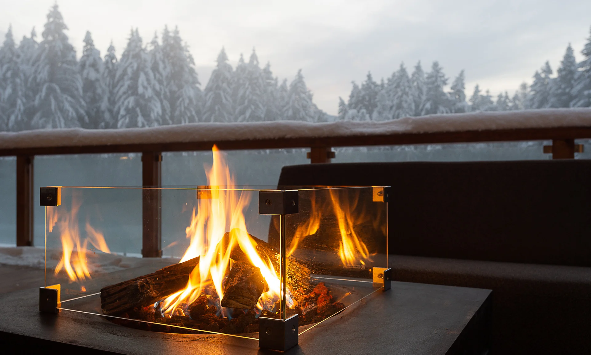 Il segreto di rallentare in questo hotel vicino a Brunico Focolare con protezione in vetro su terrazza con vista su foresta innevata