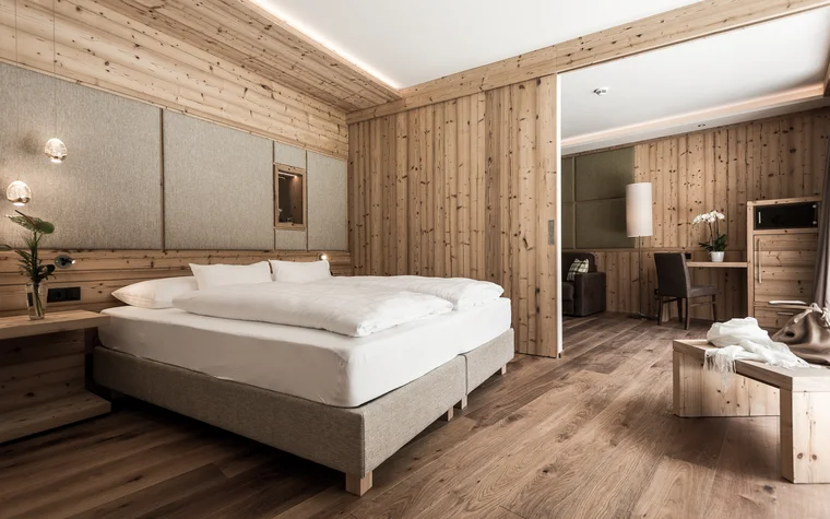 Modernes Hotelzimmer mit Holzwänden, Doppelbett und Sitzecke