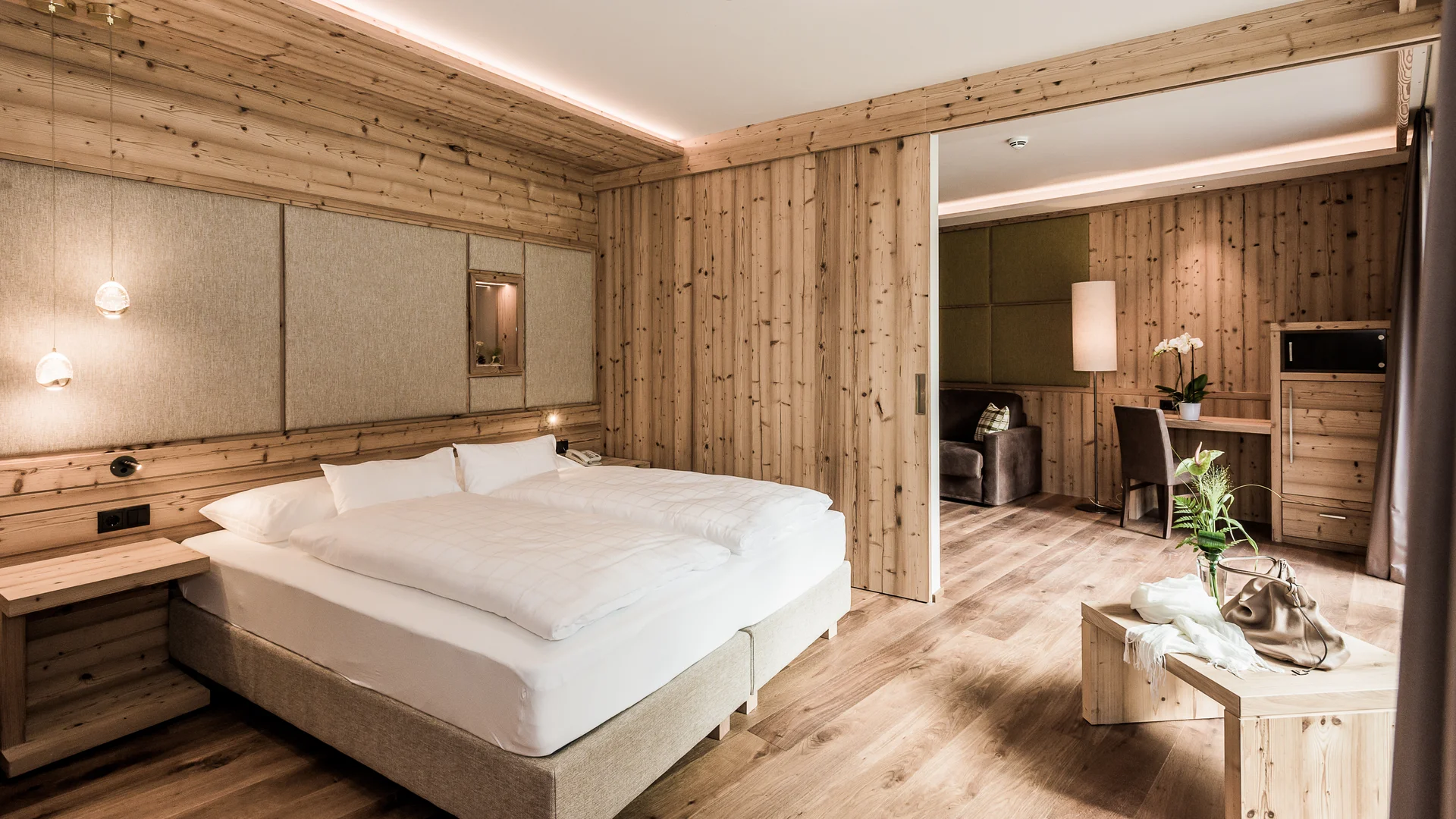 Entschleunigen und genießen in diesem Hotel nahe Bruneck Modernes Hotelzimmer mit Holzverkleidung und großem Bett