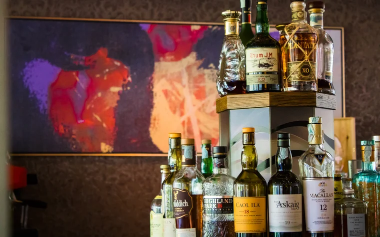 Verschiedene Flaschen alkoholischer Getränke vor abstraktem Gemälde