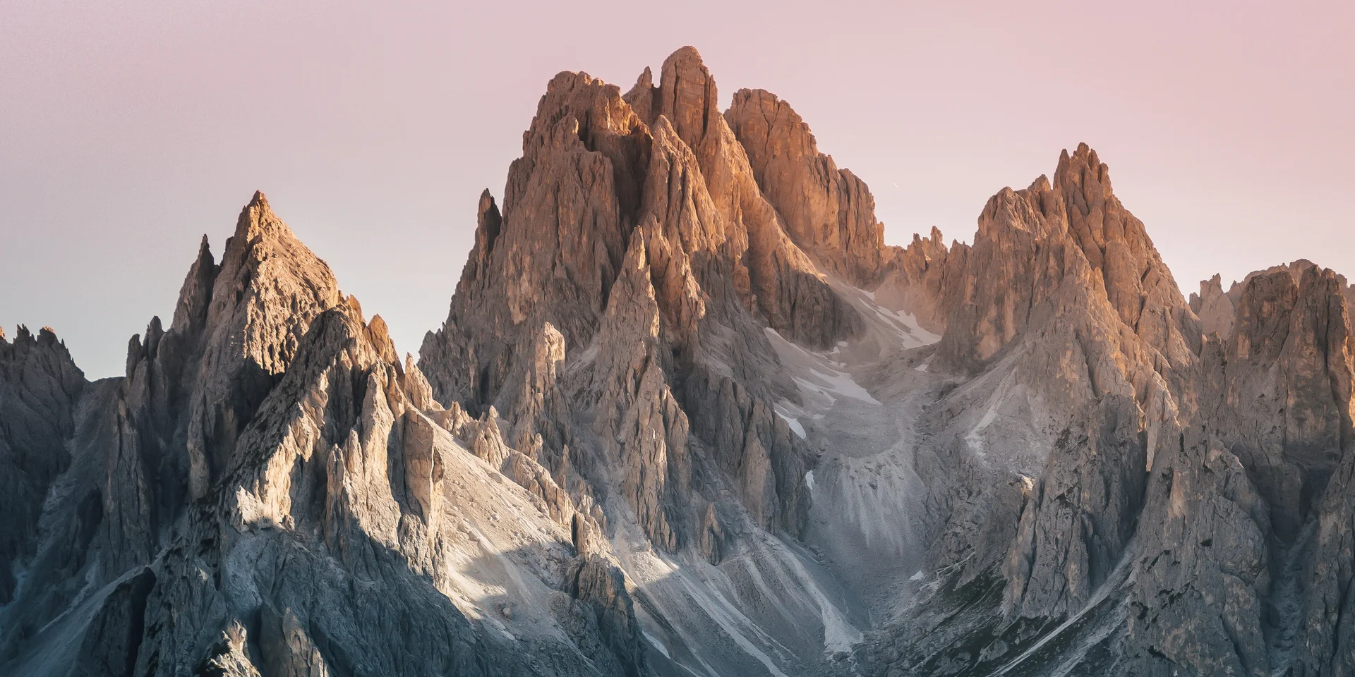 Cime rocciose illuminate dal tramonto con cielo rosa