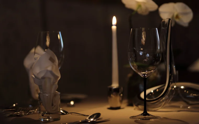 Romantisch gedeckter Tisch mit Kerze, Weingläsern und Servietten